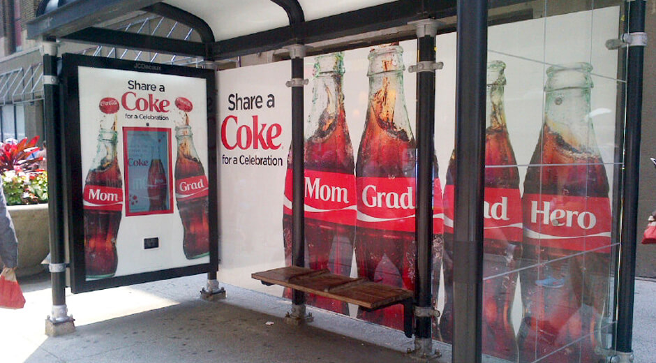 A photo of a 'Share a Coke' smile-activated can dispenser bus stop execution